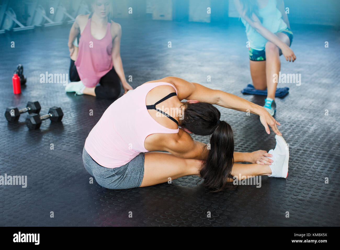 Giovane donna che allunga la gamba e il lato in palestra Foto Stock