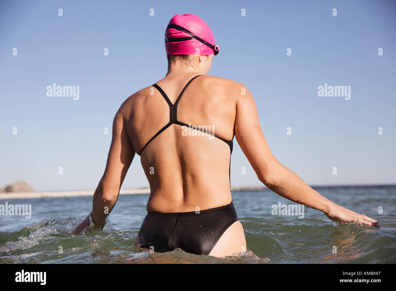 Nuotatore femminile in acqua aperta che guadi nell'oceano soleggiato Foto Stock