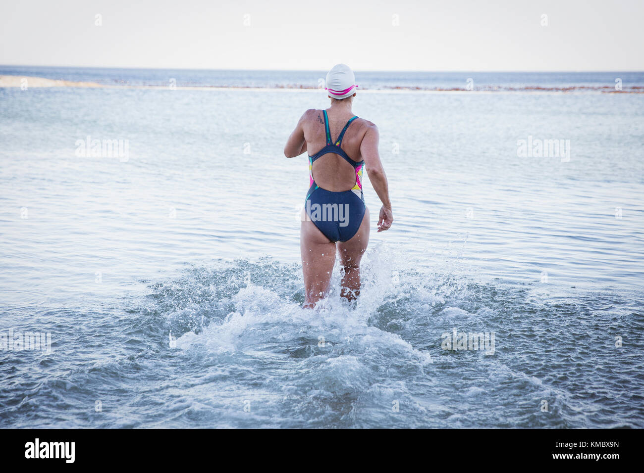 Nuotatore femminile in acqua aperta che corre nel surf oceanico Foto Stock