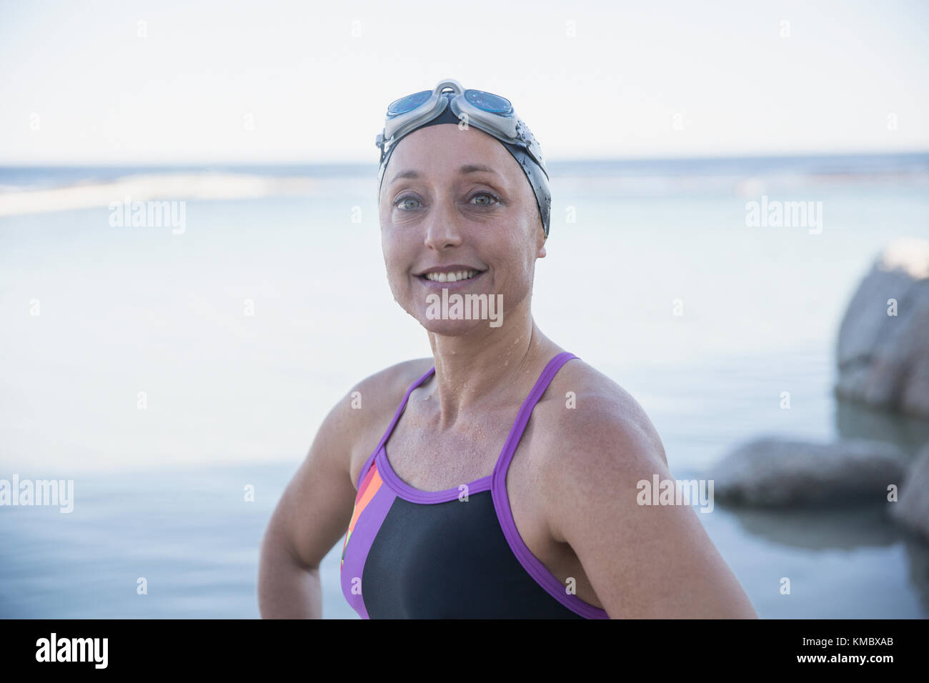 Ritratto sorridente sicuro nuotatore di acqua aperta femmina all'oceano Foto Stock