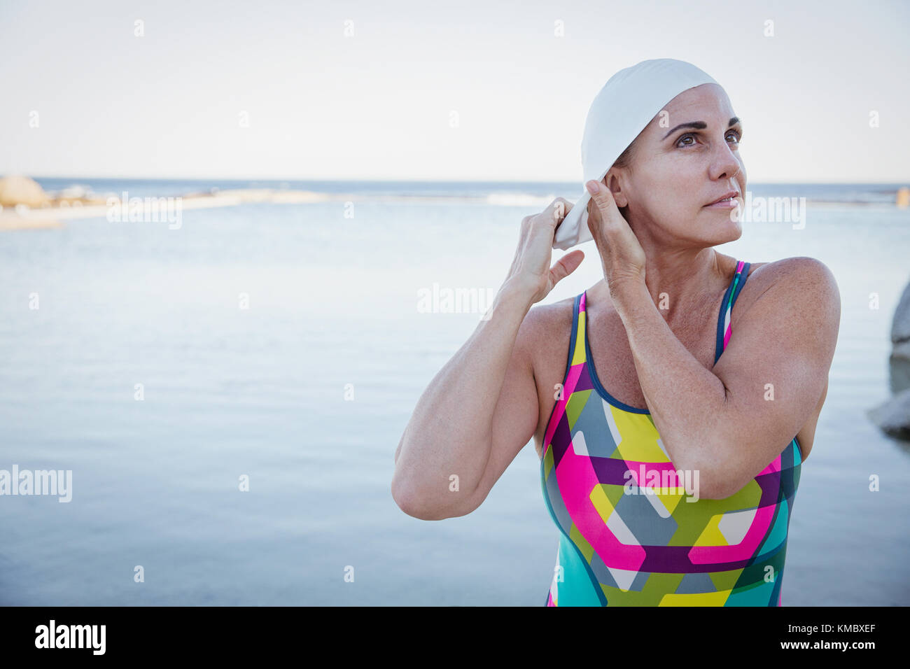 Nuotatore femminile in acqua aperta che regola la cuffia dell'oceano Foto Stock
