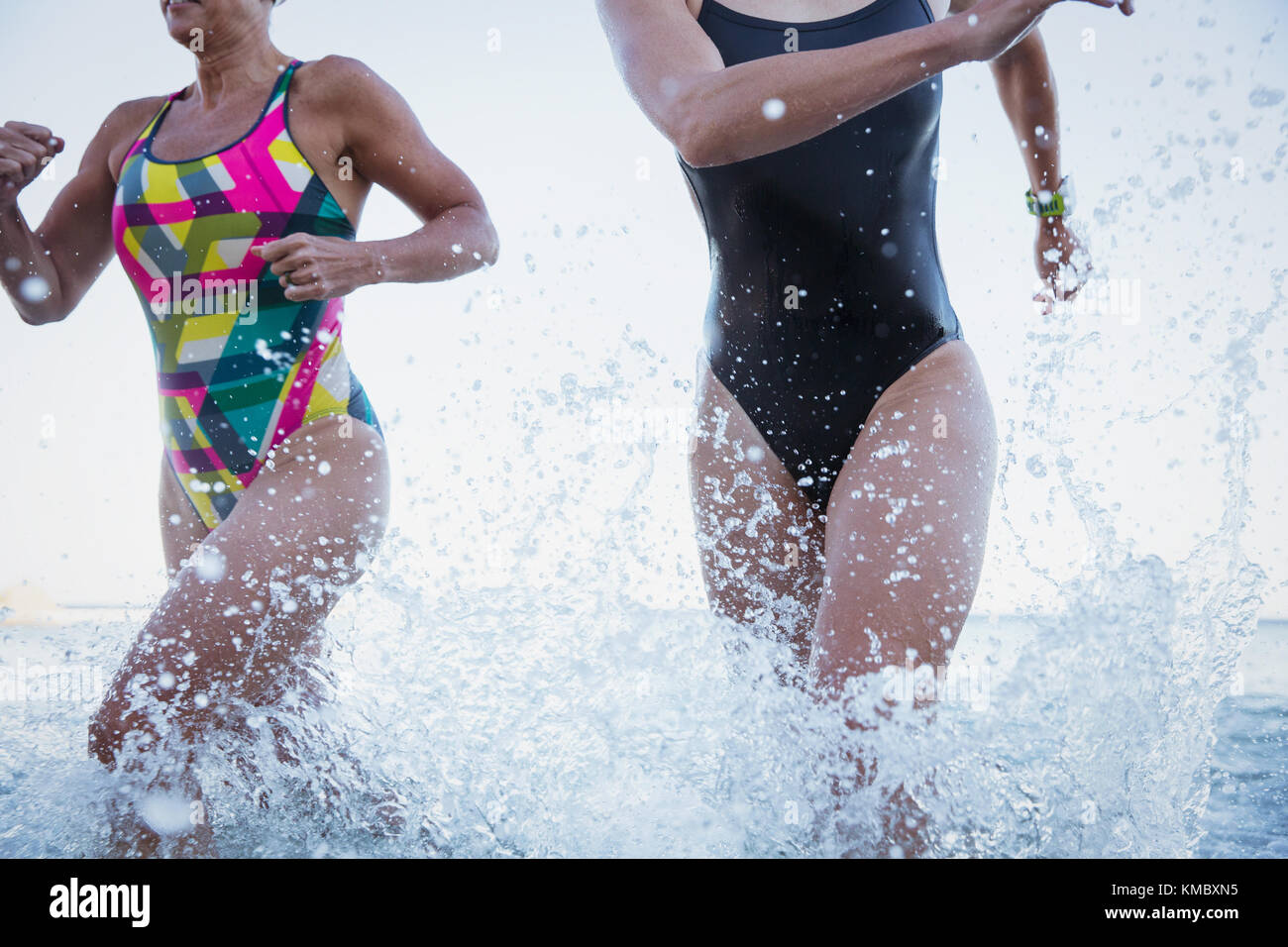 Femmina acqua aperta nuotatori in esecuzione e spruzzi in ocean surf Foto Stock