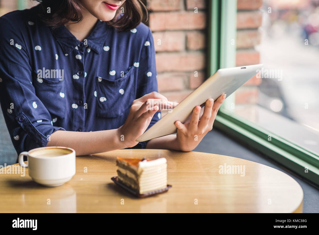 Bella carino asian giovane imprenditrice nel cafe, utilizzando tavoletta digitale e di bere il caffè sorridente Foto Stock