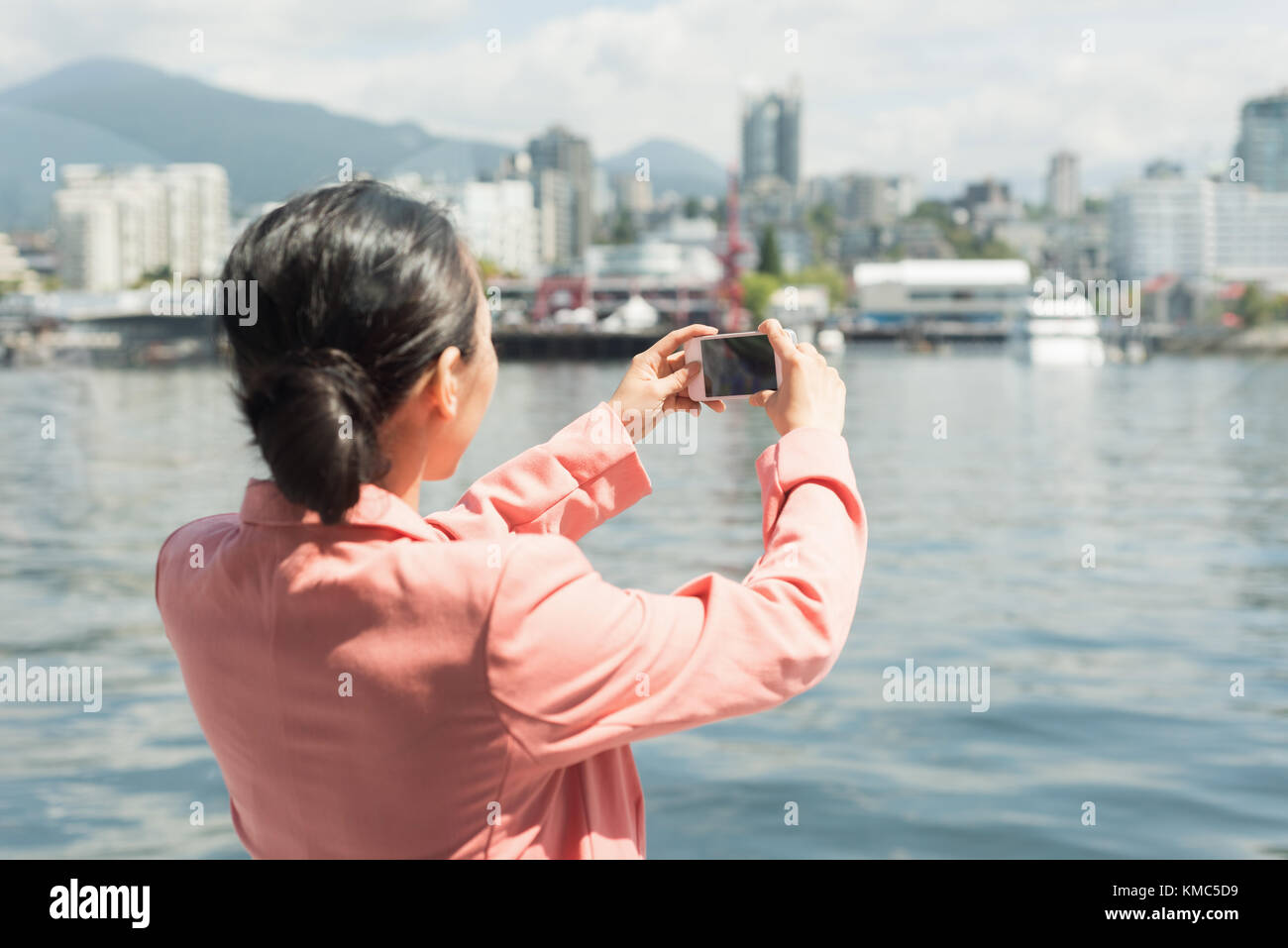 Donna asiatica che scatta una foto dello skyline dal traghetto Foto Stock