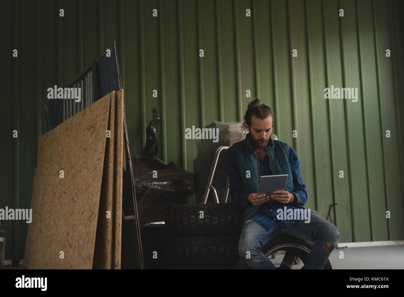 Uomo seduto sul pneumatico e utilizzando un tablet digitale Foto Stock