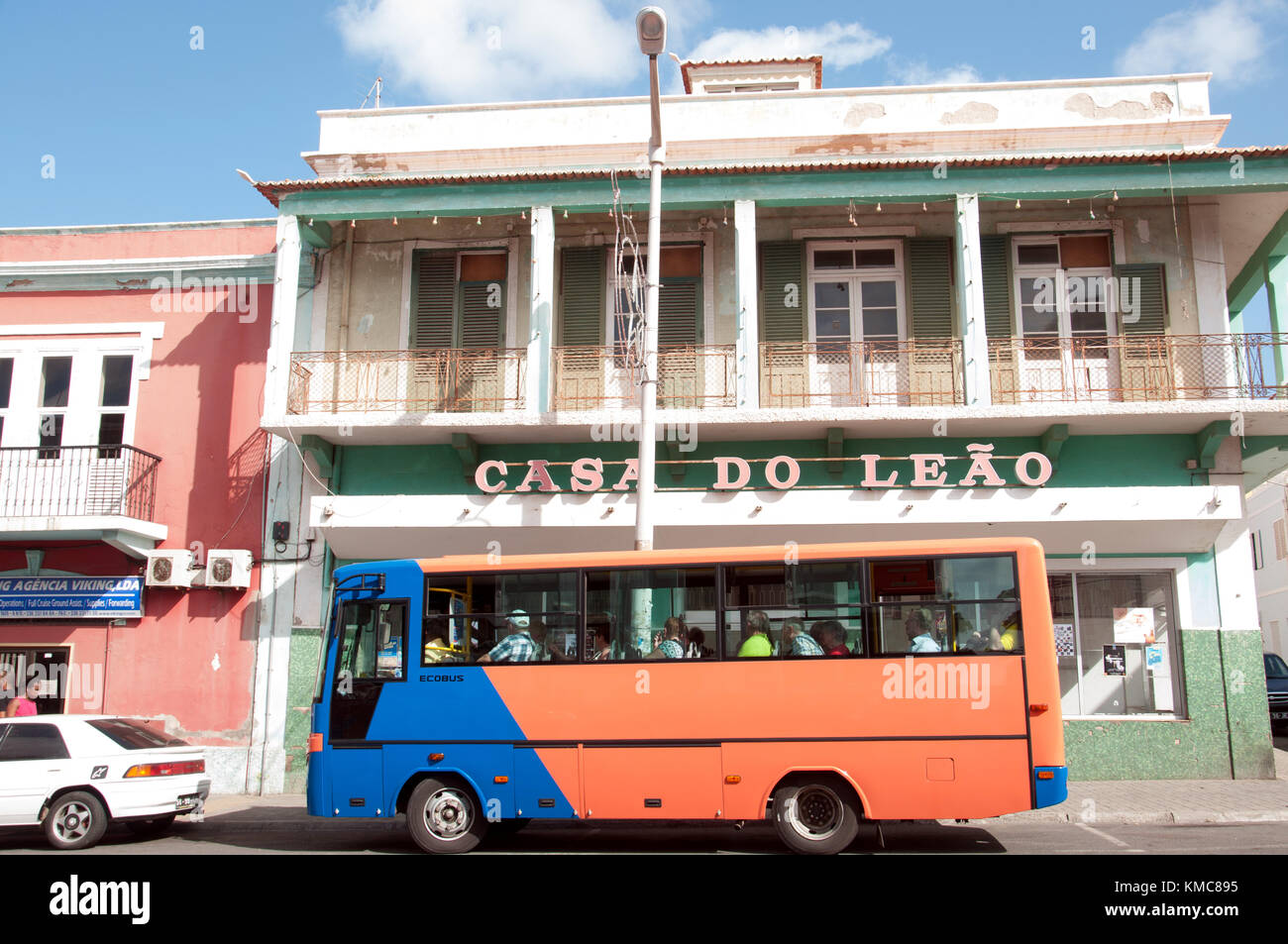 L'autobus di colore brghoso passa accanto a un edificio di nome portoghese nella strada principale, Rua de Lisboa, a Mindelo, capitale dell'isola di São Vicente nell'arcipelago del Capo Verde Foto Stock
