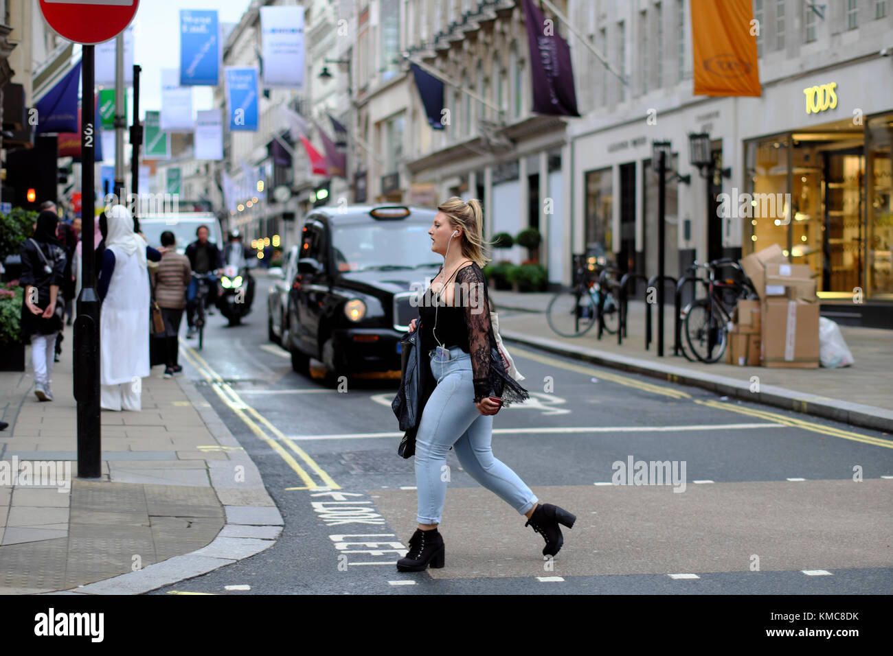 Donne camminando per strada di fronte all Taxi su Old Bond Street, Londra, Inghilterra, Regno Unito Foto Stock