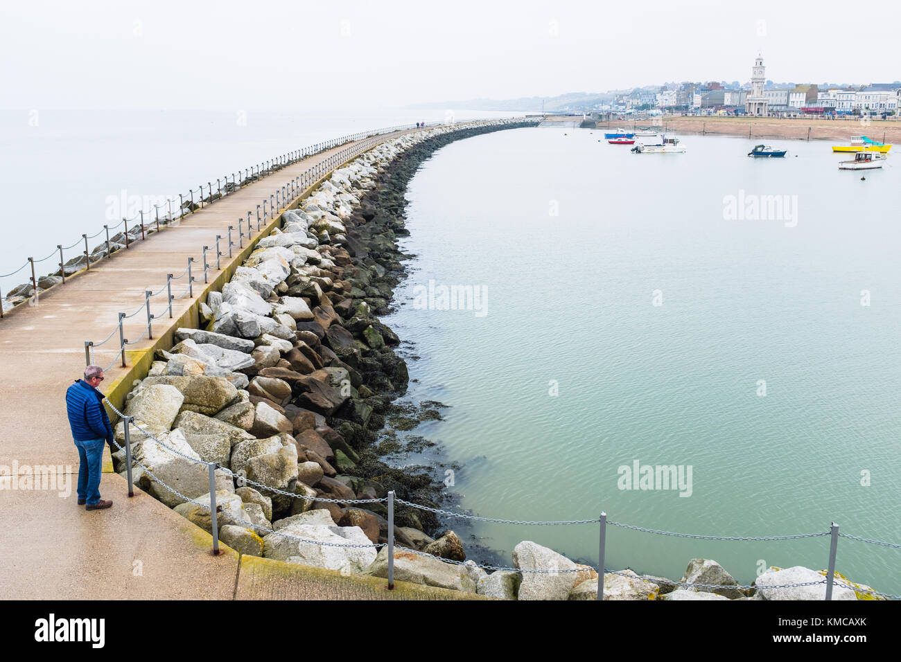 HERNE BAY, Inghilterra - Ott 18 2017. Un uomo locale sorge alla fine dell'offshore frangiflutti noti come Nettuno braccio, costruito negli anni novanta a proteggere la città Foto Stock