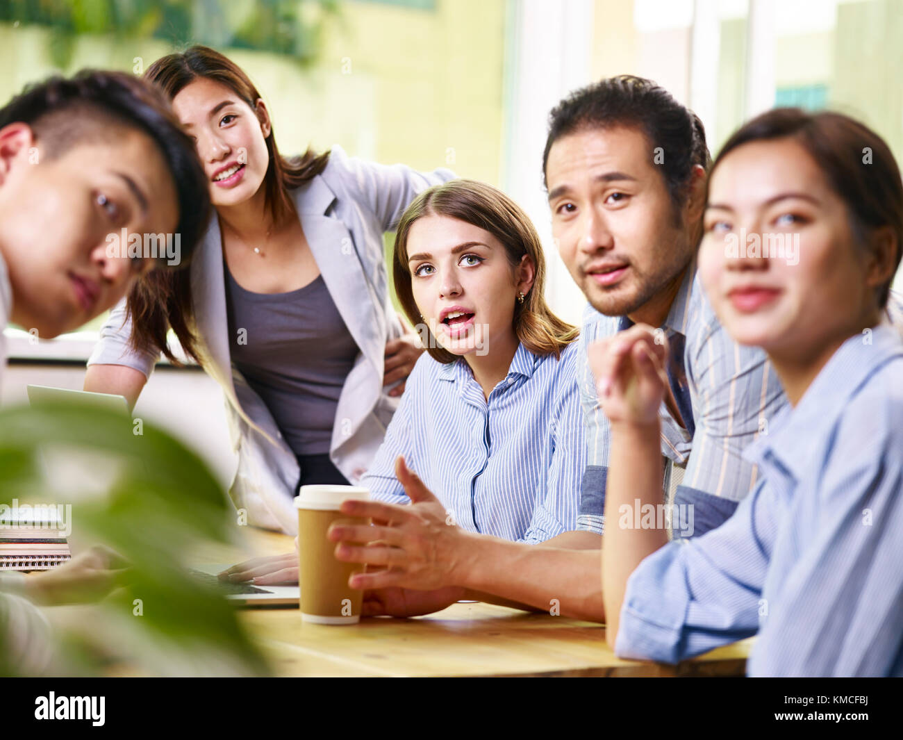 Team di giovani asiatici e caucasici imprenditori maschio e femmina di riunione in ufficio. Foto Stock