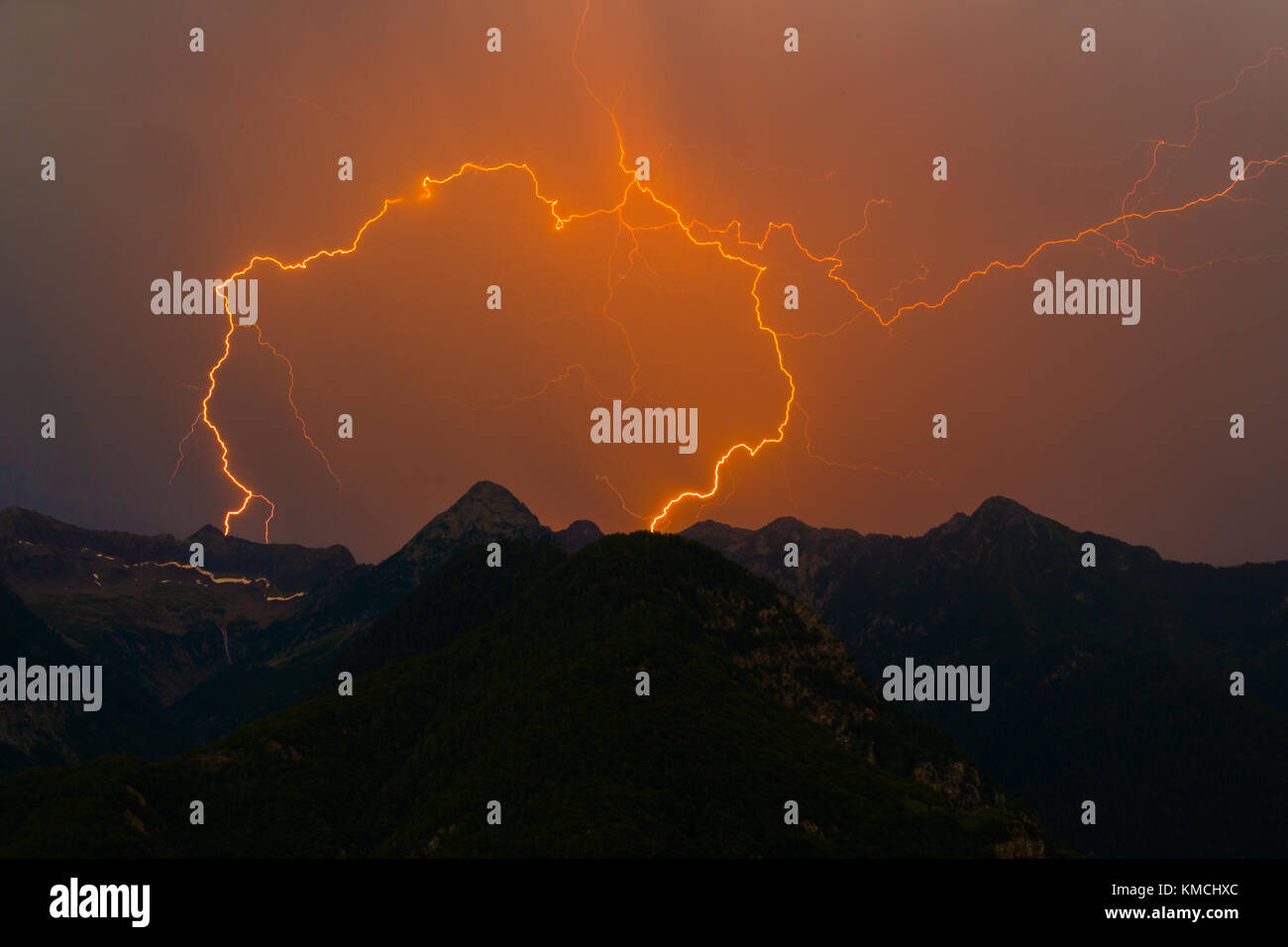Natural spettacolare doppia fulmine sciopero nel picco di montagna silhouette, cielo arancione Foto Stock