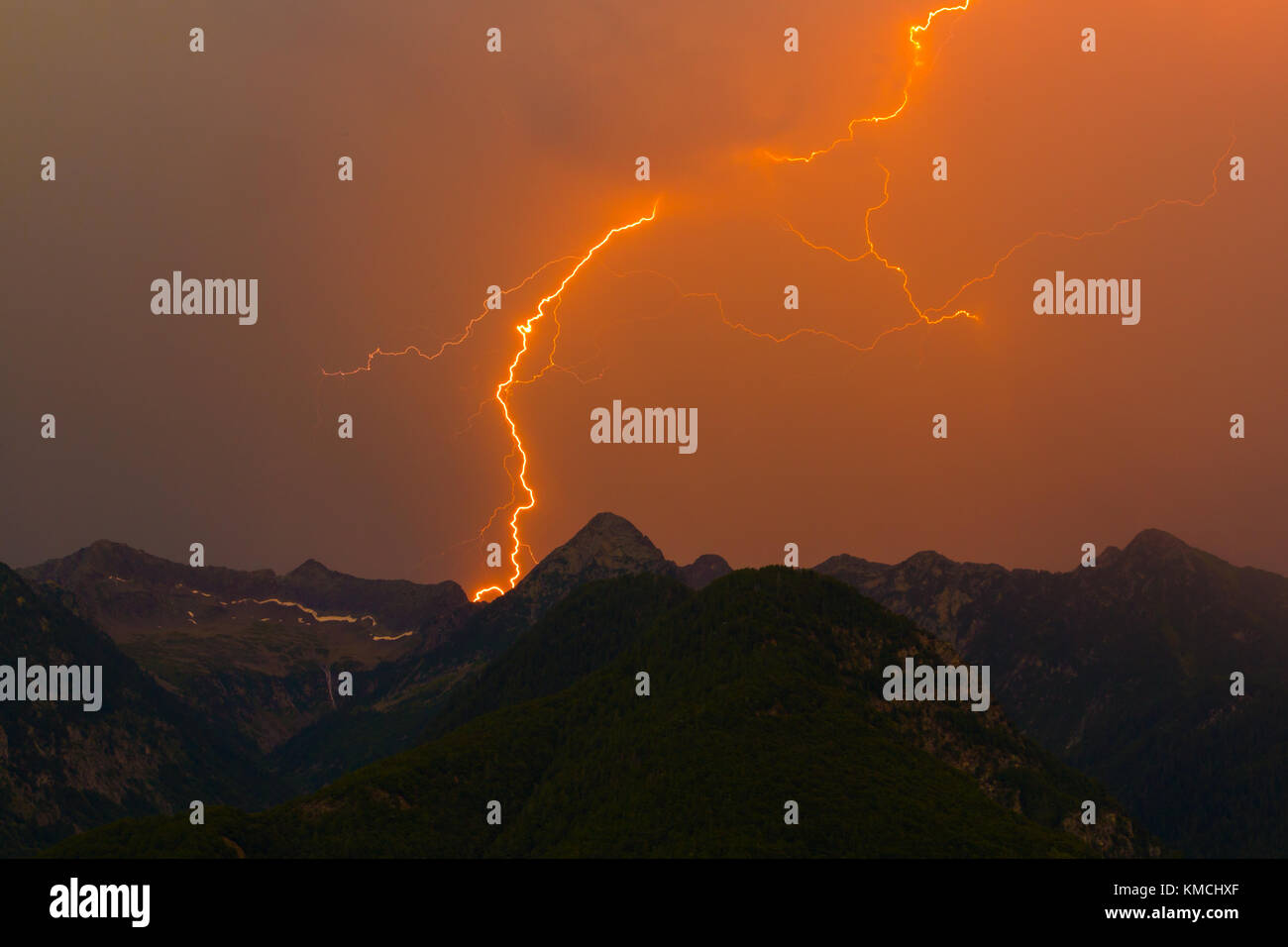 Spettacolare naturale di fulmine sciopero nel picco di montagna silhouette, orange sky, cloud Foto Stock