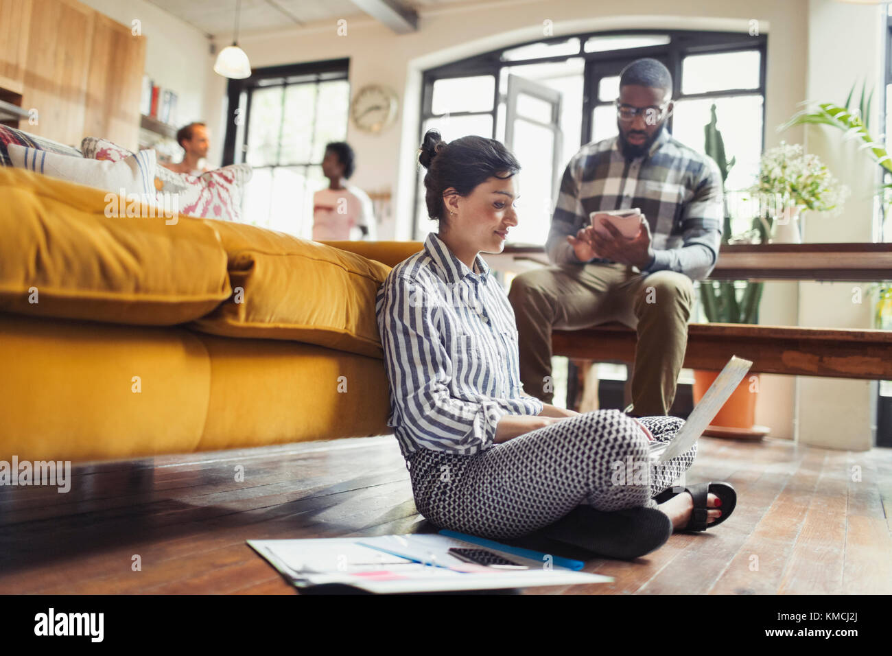 Freelance femminile che lavora su un computer portatile sul pavimento del soggiorno Foto Stock