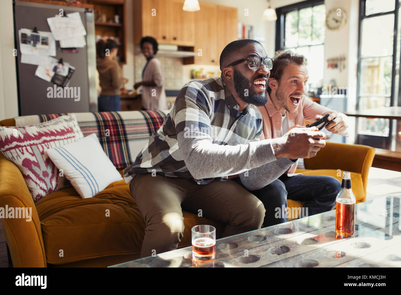 Amici di sesso maschile bere birra e giocare a videogiochi in vita camera Foto Stock