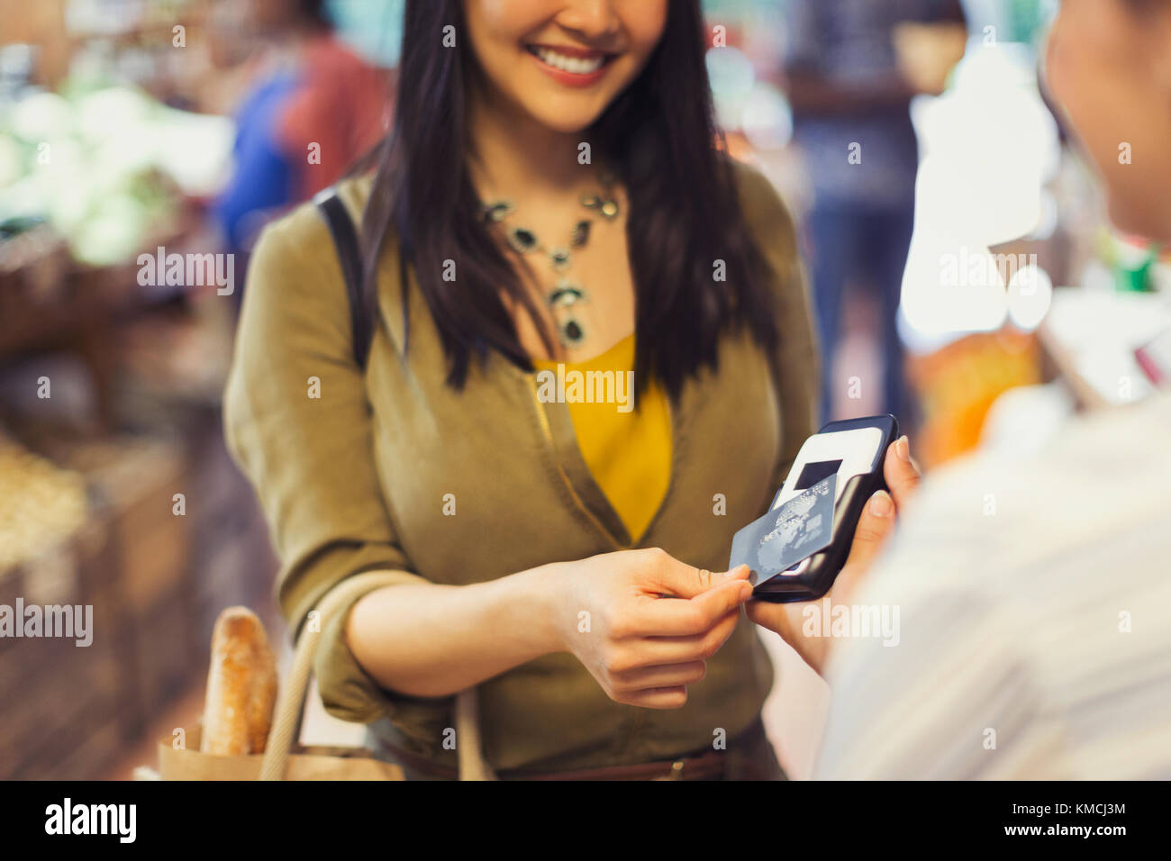 Giovane donna che paga cassa con contactless carta di credito pagamento in negozio Foto Stock