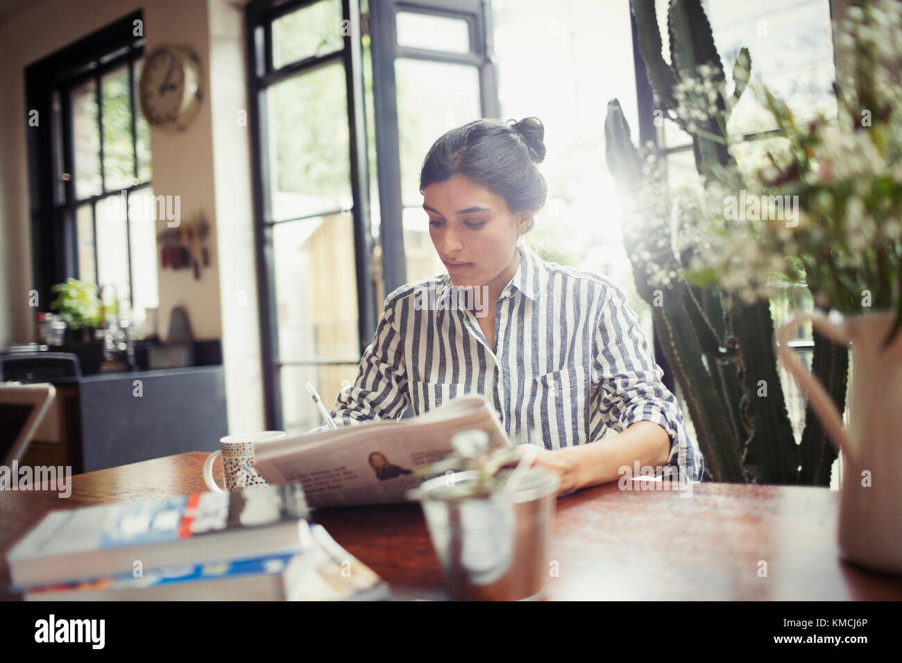 Giovane donna con giornale in sala da pranzo Foto Stock