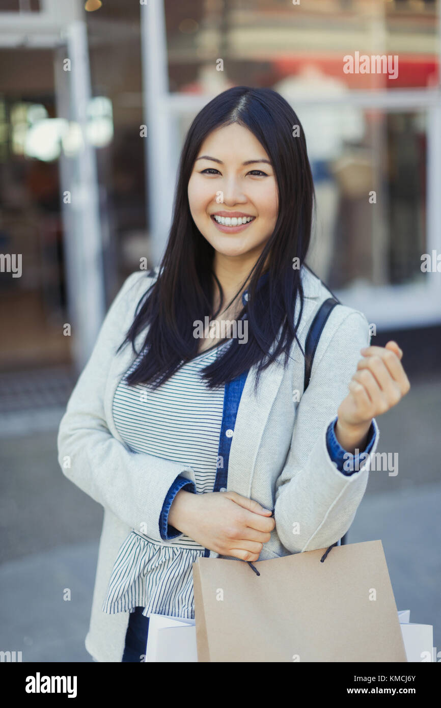 Ritratto sorridente giovane donna con borse Foto Stock