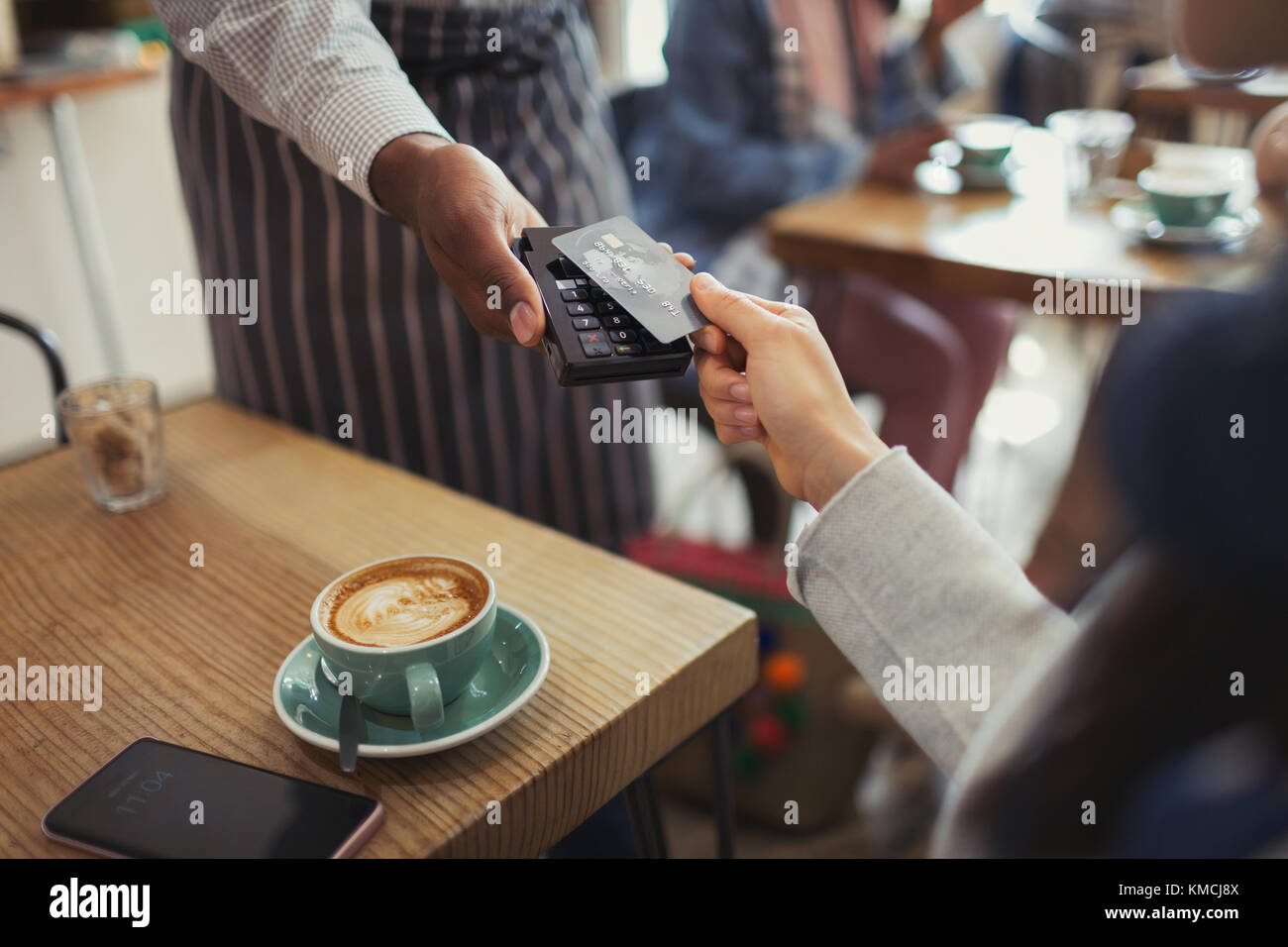 Cliente con carta di credito lavoratore pagante con contactless pagamento in caffè Foto Stock
