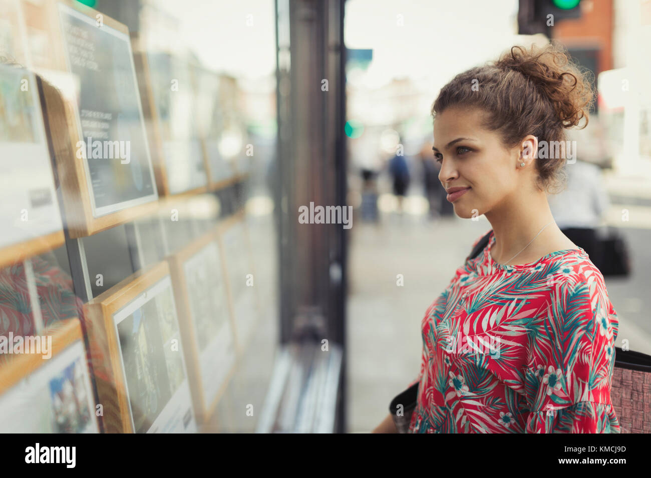 Giovane donna che naviga gli elenchi di immobili in urban storefront Foto Stock