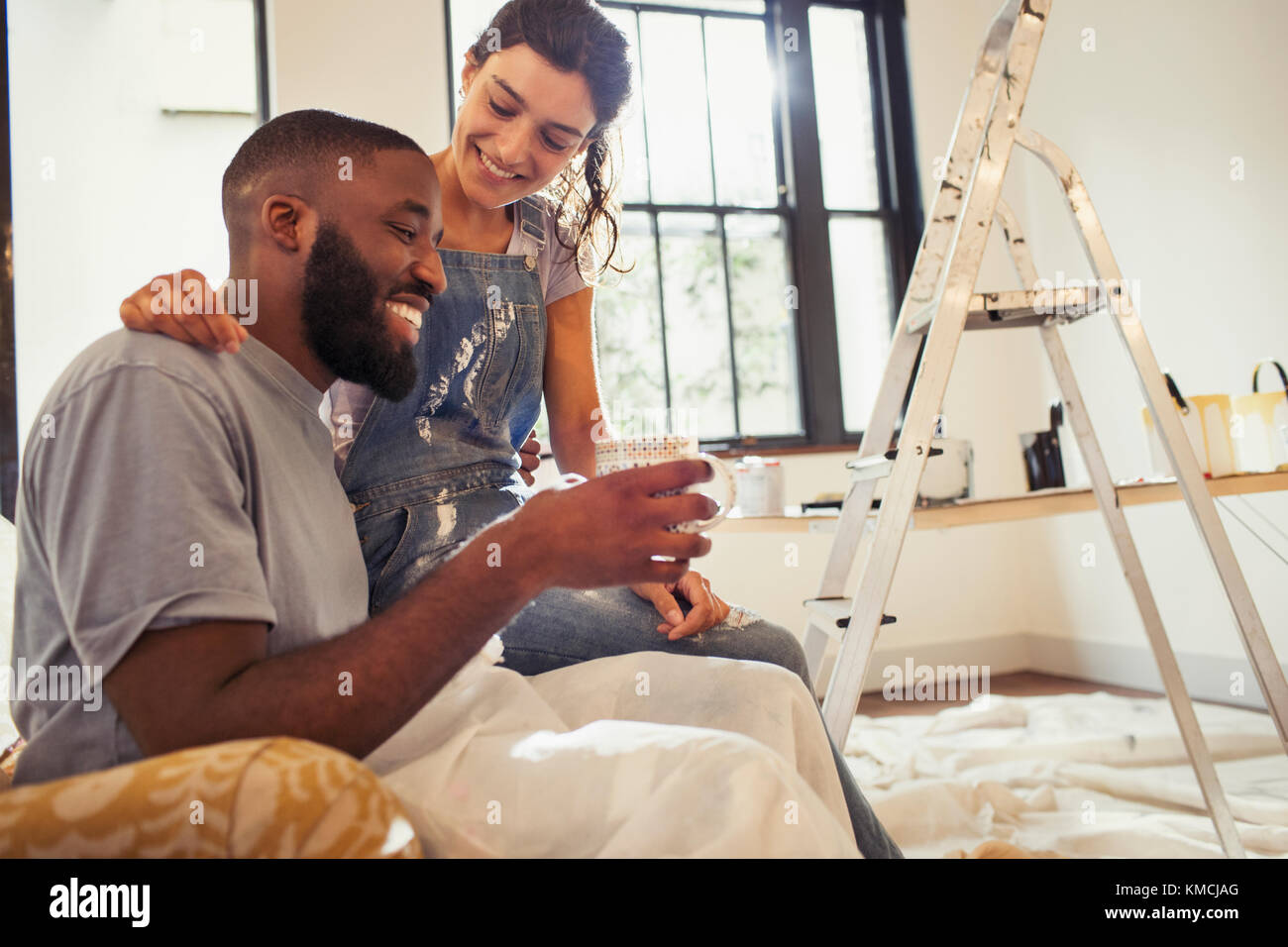 Affettuosa giovane coppia bevendo caffè e dipingendo soggiorno Foto Stock