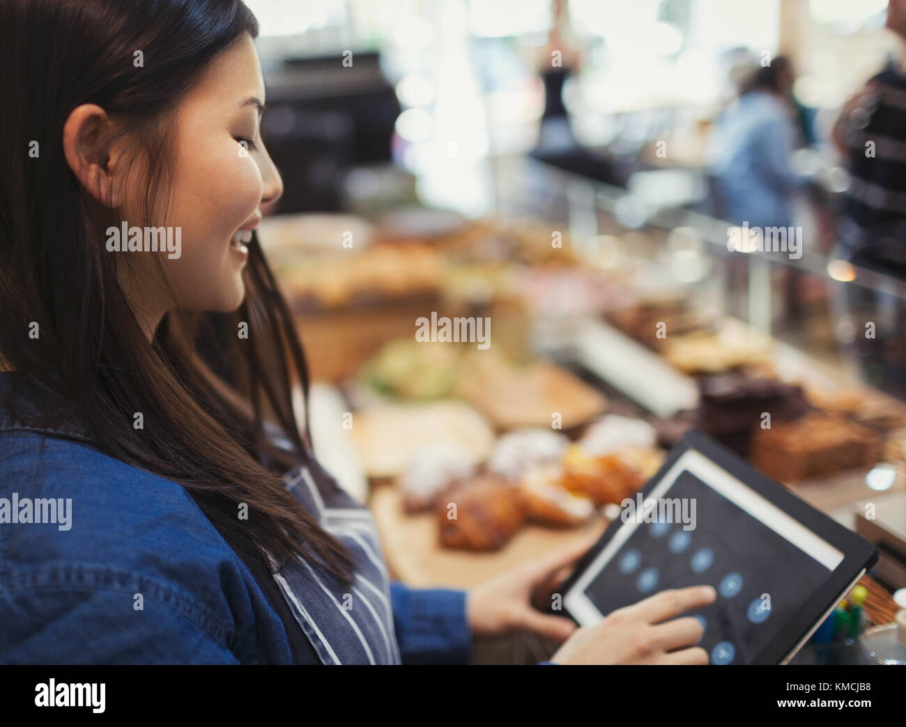 Cassa sorridente utilizzando il registratore di cassa touch screen nel bar Foto Stock