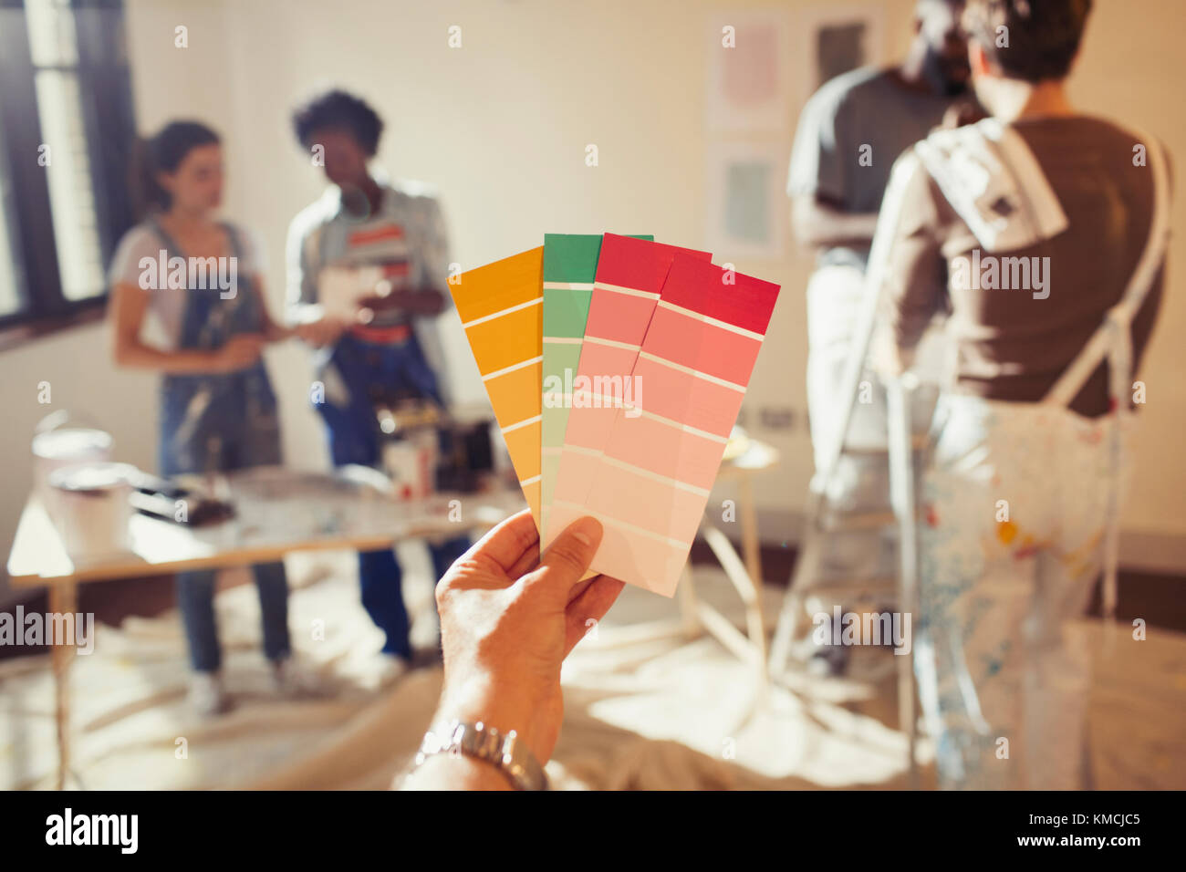 Prospettiva personale amici che guardano campioni di colore, dipingendo salotto Foto Stock