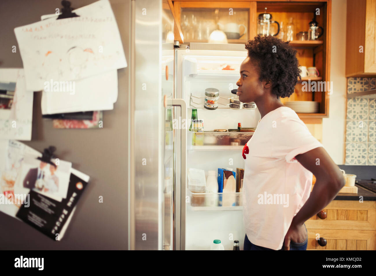 Donna affamata sbirciata in frigorifero in cucina Foto Stock