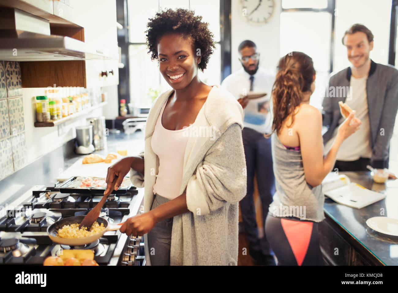 Ritratto sorridente donna che cucina uova strapazzate al piano cottura in cucina Foto Stock
