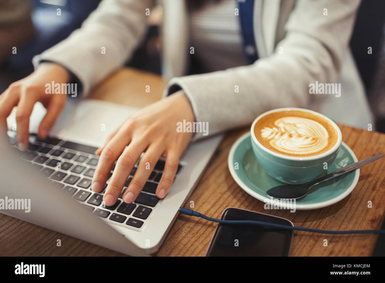 Mani di giovane donna che usano il computer portatile, cappuccino che beve nel caffè Foto Stock