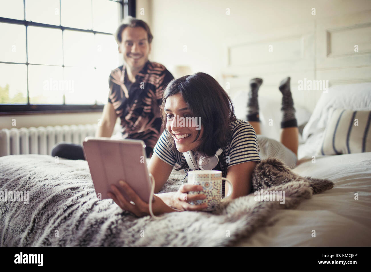 Coppia sorridente rilassante, bere caffè e utilizzare un tablet digitale a letto Foto Stock