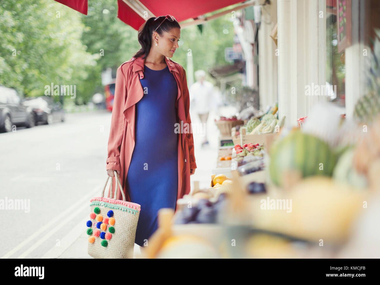 Donna incinta che acquista prodotti al mercato di fronte Foto Stock