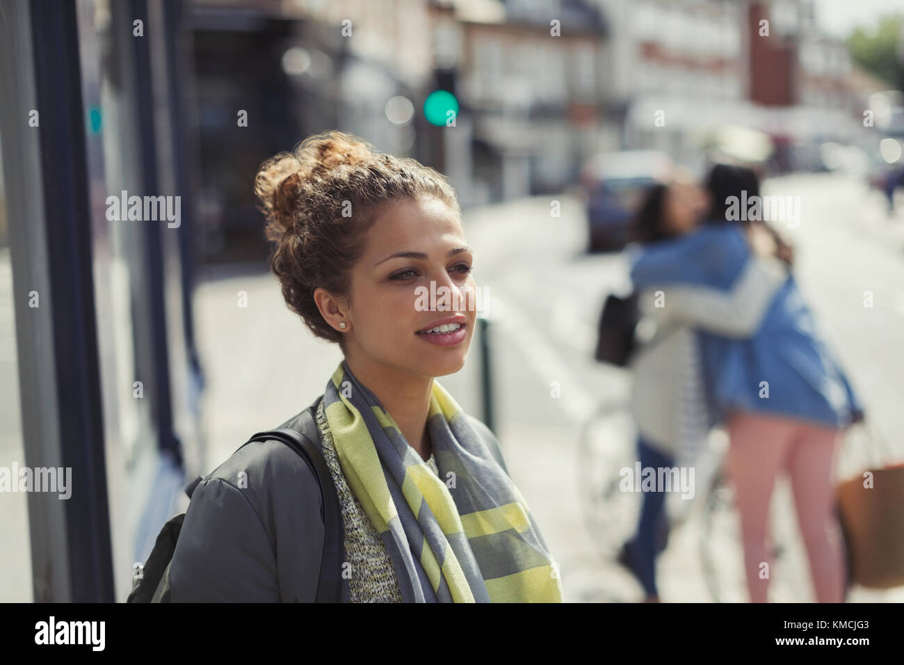 Giovane donna pensiva che guarda via sulla strada urbana soleggiata Foto Stock