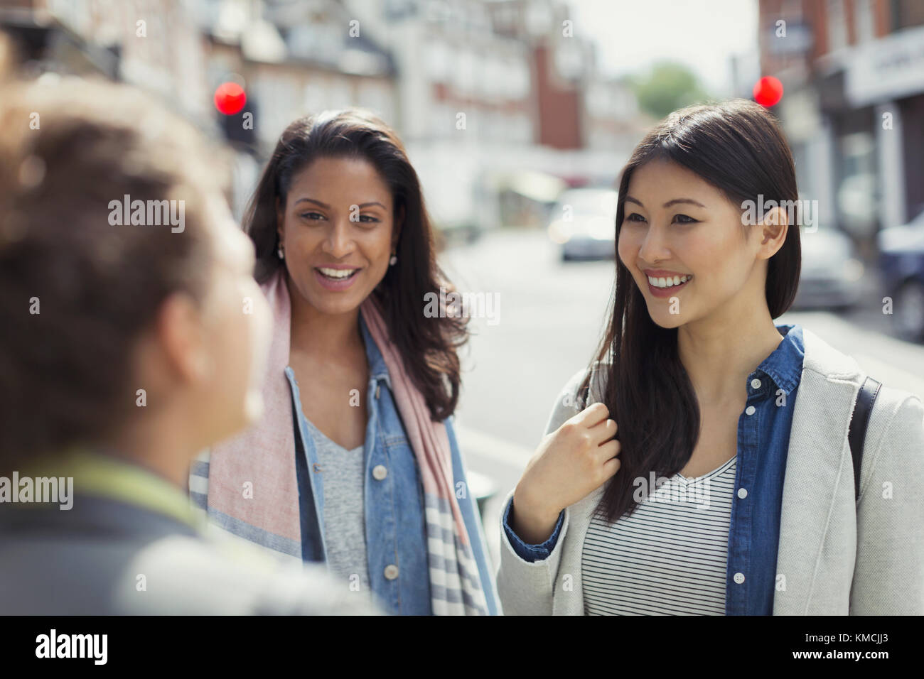 Sorridenti amici donne che parlano su strada urbana Foto Stock