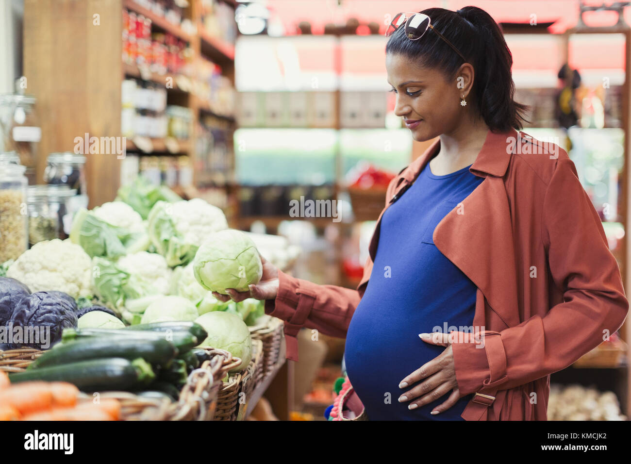 Donna incinta che acquista cavolo in un negozio di alimentari Foto Stock