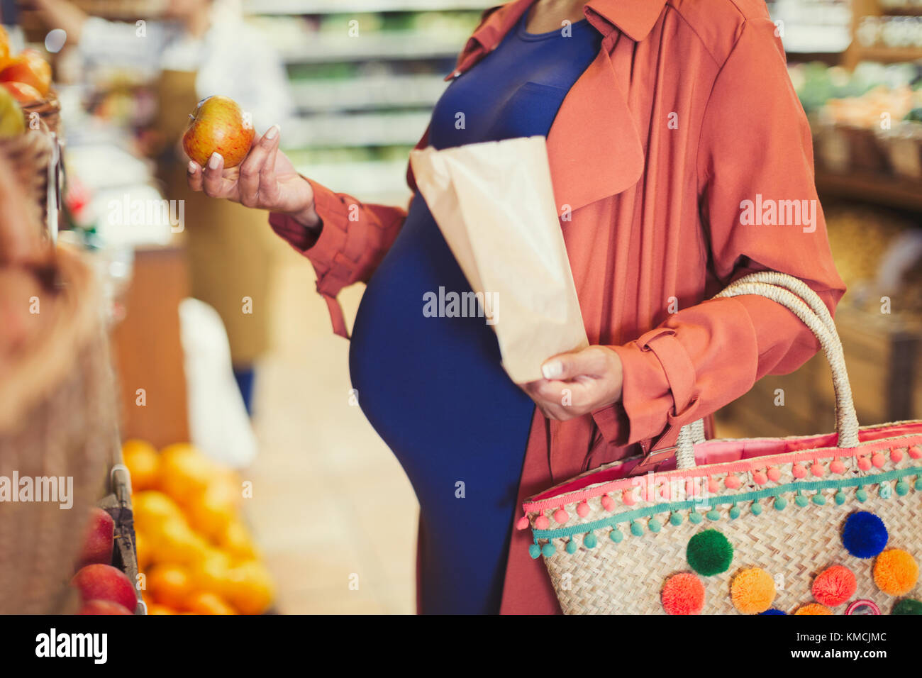 Donna incinta che acquista mele in un negozio di alimentari Foto Stock