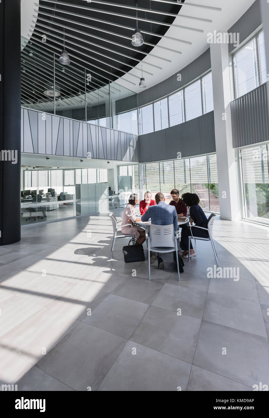 Gli uomini d'affari si riunano al tavolo nell'atrio dell'ufficio moderno Foto Stock