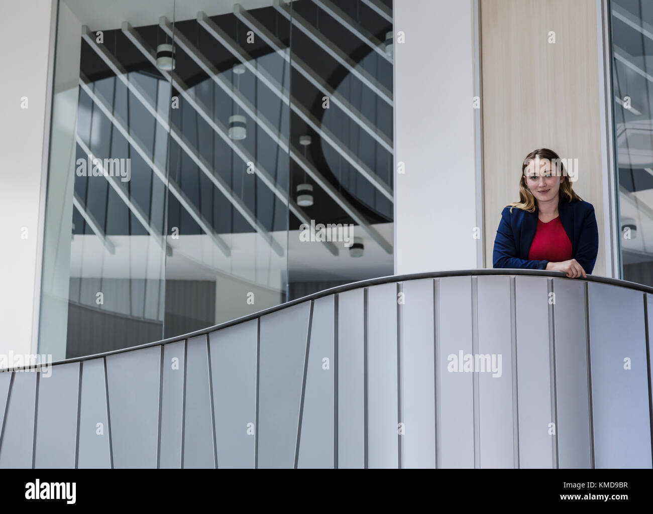 Ritratto sorridente, donna d'affari sicura in piedi sul moderno balcone dell'ufficio Foto Stock