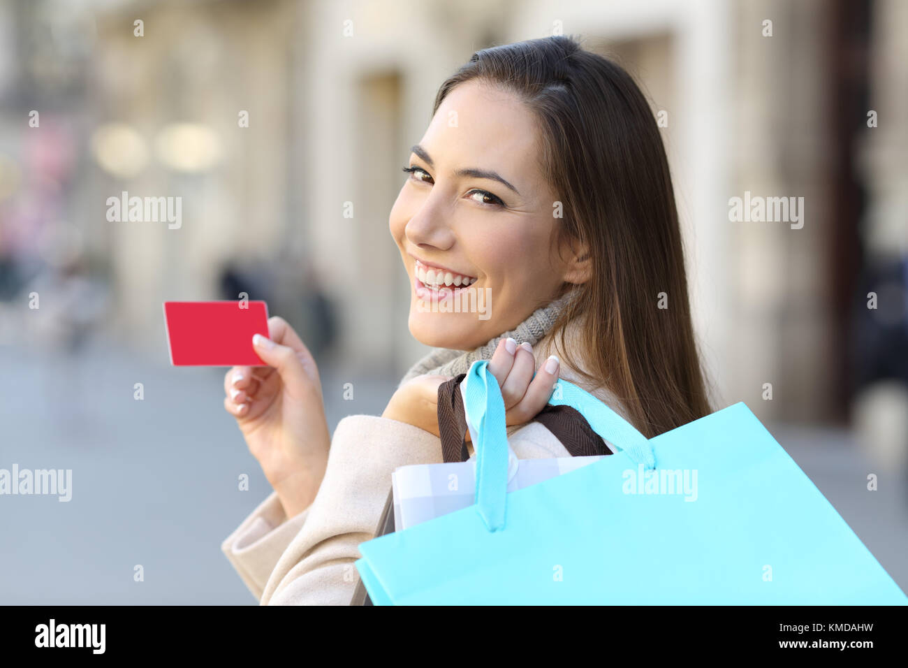 Ritratto di un felice shopper azienda borse per lo shopping e una carta di credito sulla strada Foto Stock