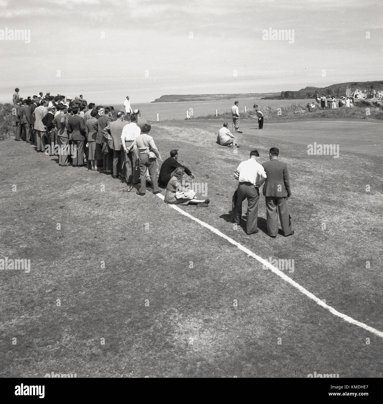 1951, storico, al Royal Portrush Golf Club sulla costa di Antrim, Irlanda del Nord, si svolge il British Open Championship - ora noto come semplicemente Open Championship - con spettatori riuniti intorno a uno dei verdi costieri per guardare il putt golfisti. Ora noto come semplicemente 'The Open', questo evento è stato vinto dal golfista inglese Max Faulkner, la sua vittoria unica maggiore. Foto Stock