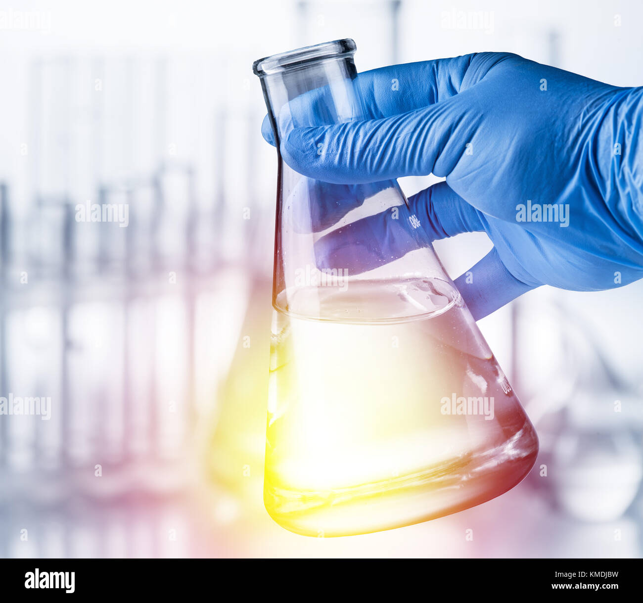 Bicchiere da laboratorio in analyst la mano nel guanto di plastica. Foto Stock