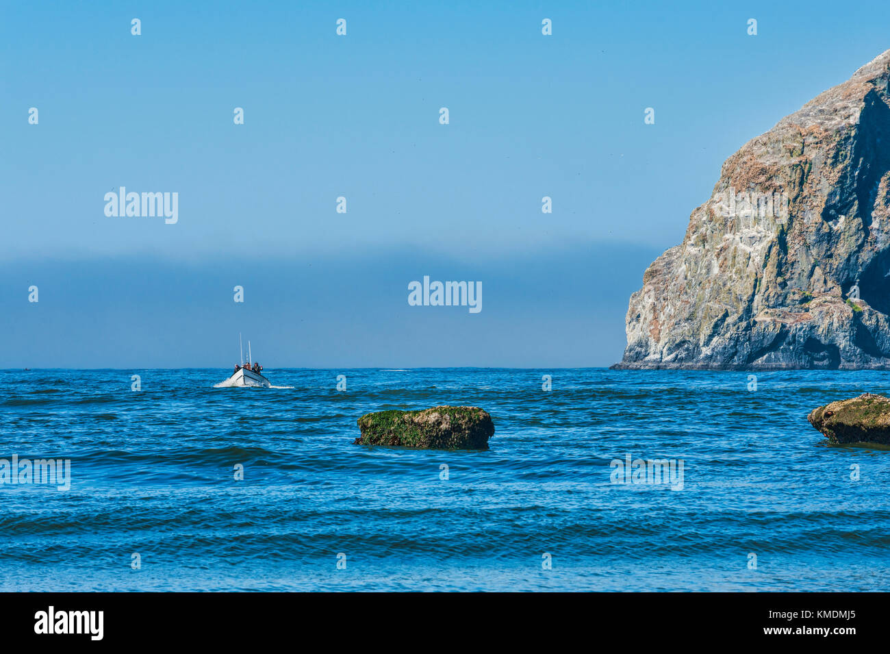 Città del Pacifico, Oregon, Stati Uniti d'America - 2 Luglio 2, 2015: una barca dory passa da Haystack Rock come fa il suo approccio al terreno sulla spiaggia di Cape Kiwanda Foto Stock