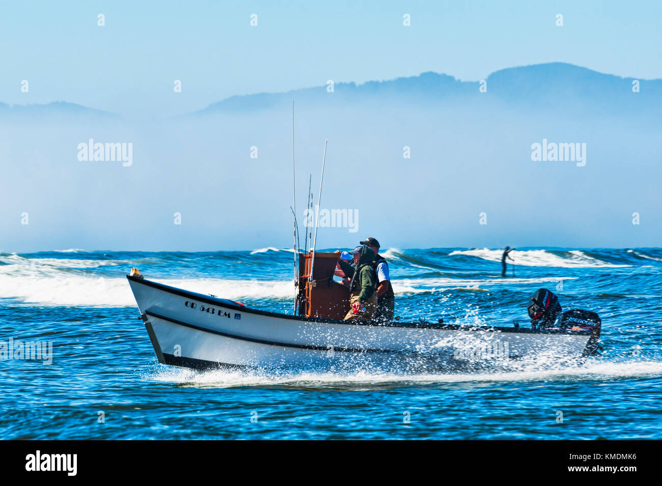 Città del Pacifico, Oregon, Stati Uniti d'America - 2 Luglio 2, 2015: una barca dory crest un'onda mentre una racchetta board persona passaggio nella direzione opposta. Dory captians sono cons Foto Stock