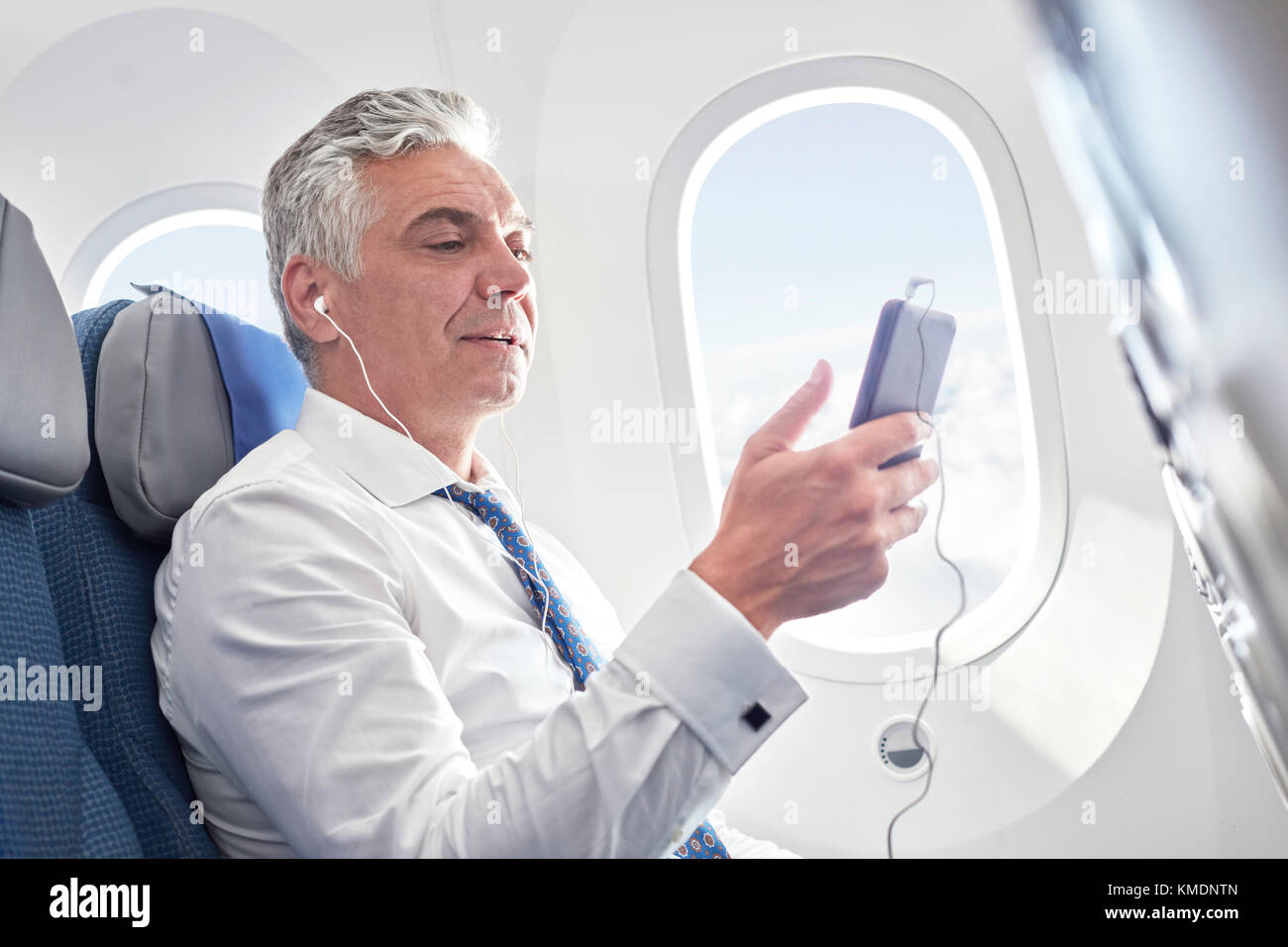 Uomo d'affari che ascolta la musica con le cuffie e il lettore mp3 aereo Foto Stock