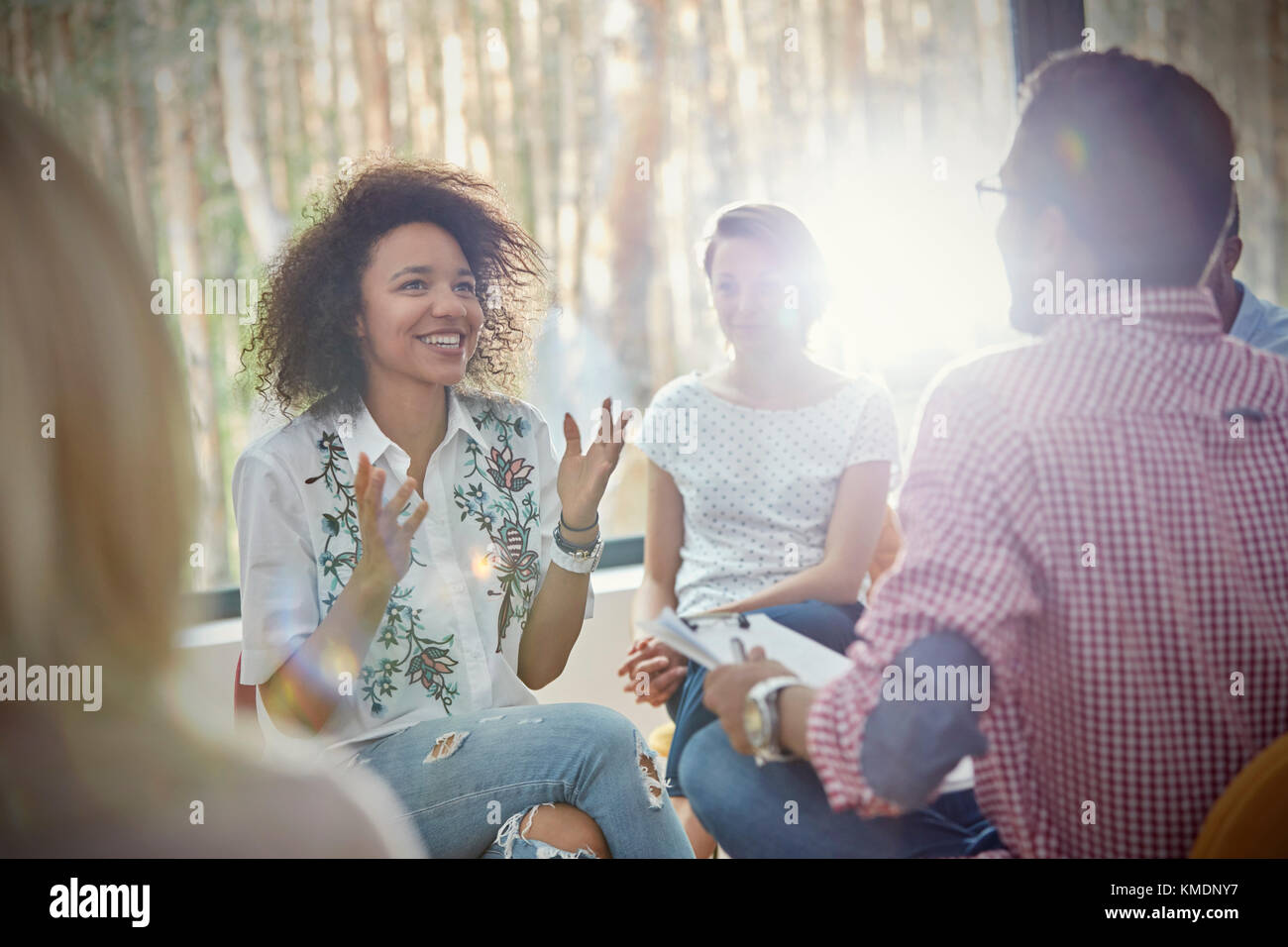 Donna sorridente parlando e gesticolando in terapia di gruppo a sessione Foto Stock