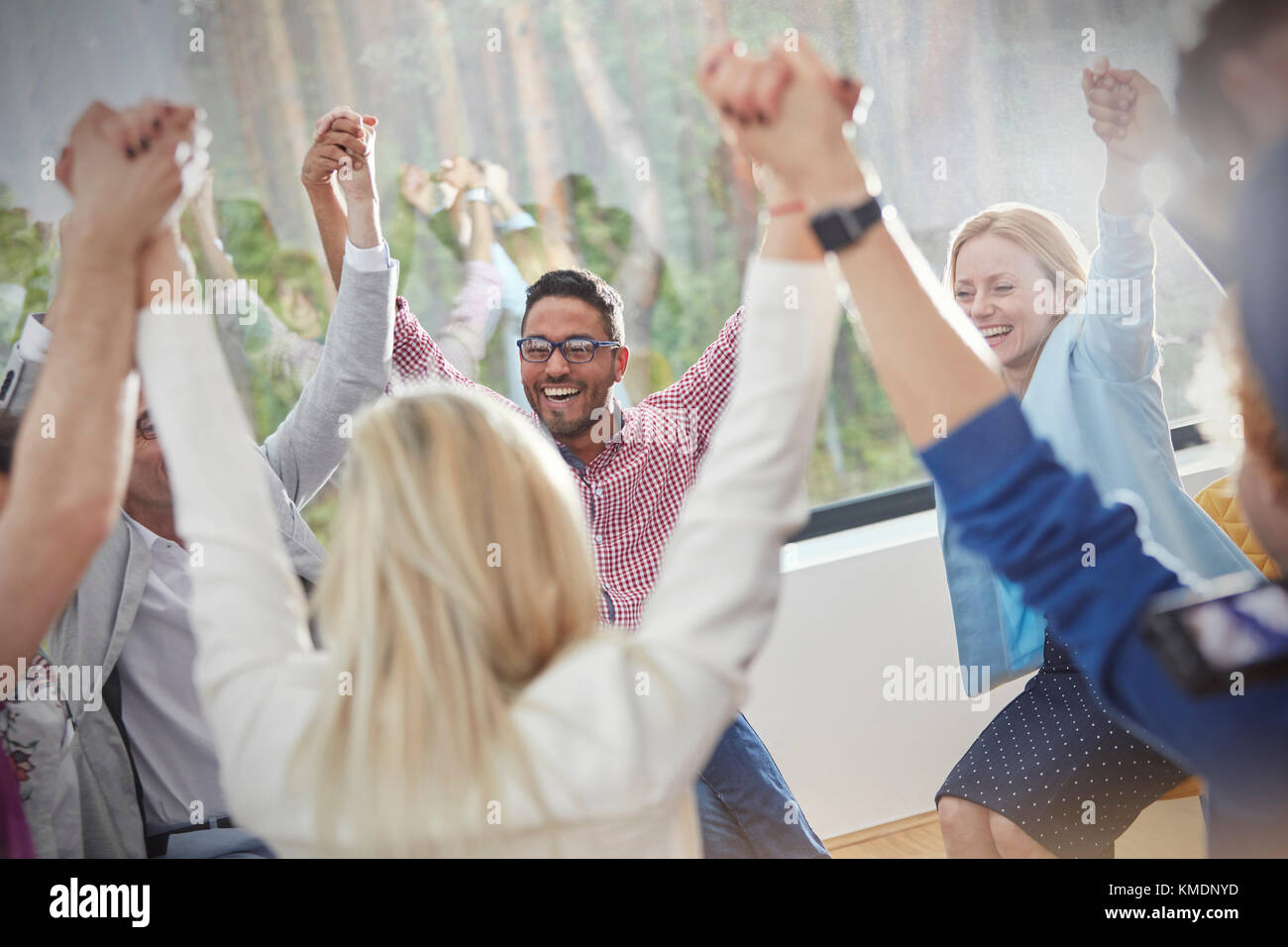 Persone sorridenti e tenendo le mani in cerchio in una terapia di gruppo a sessione Foto Stock