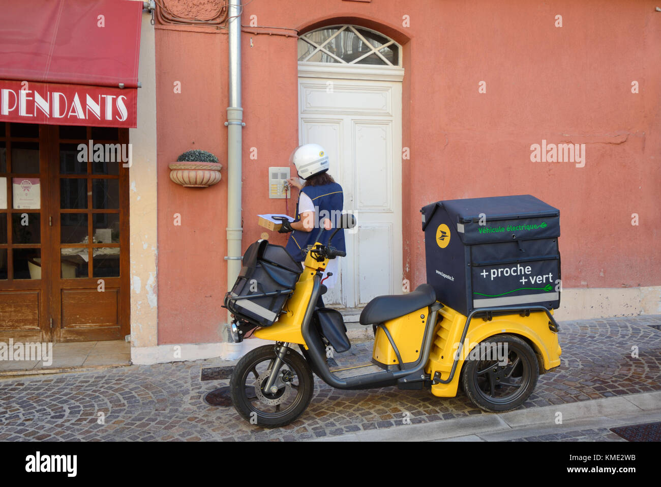 Postman francese o addetto postale che consegna lettere utilizzando il triciclo elettrico nella città vecchia di le Suquet, Cannes, Alpes-Maritimes, Francia Foto Stock