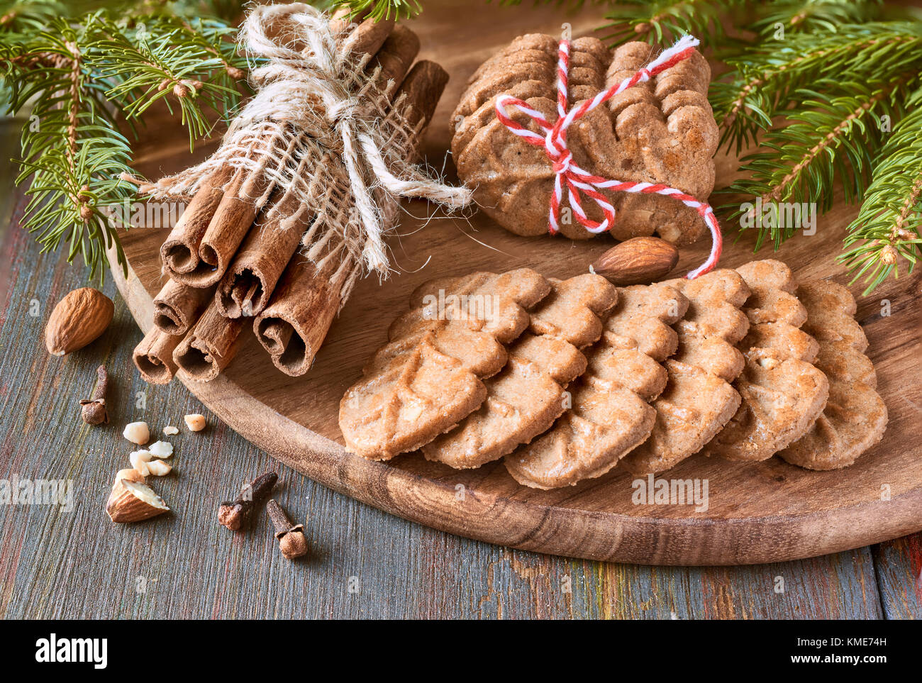 Il tempo di Natale, closeup su biscotti di mandorle con bastoncini di cannella, trifogli, mandorle e albero di Natale ramoscelli rustico sfondo di legno Foto Stock