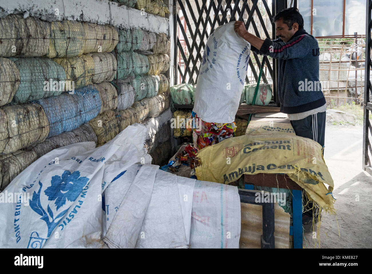 Un uomo la miscelazione fino involucri di plastica prima della loro trasformazione per fare mattoni di plastica per evitare effetti nocivi di materie plastiche, essa contribuisce alla sviluppo sostenibile Foto Stock