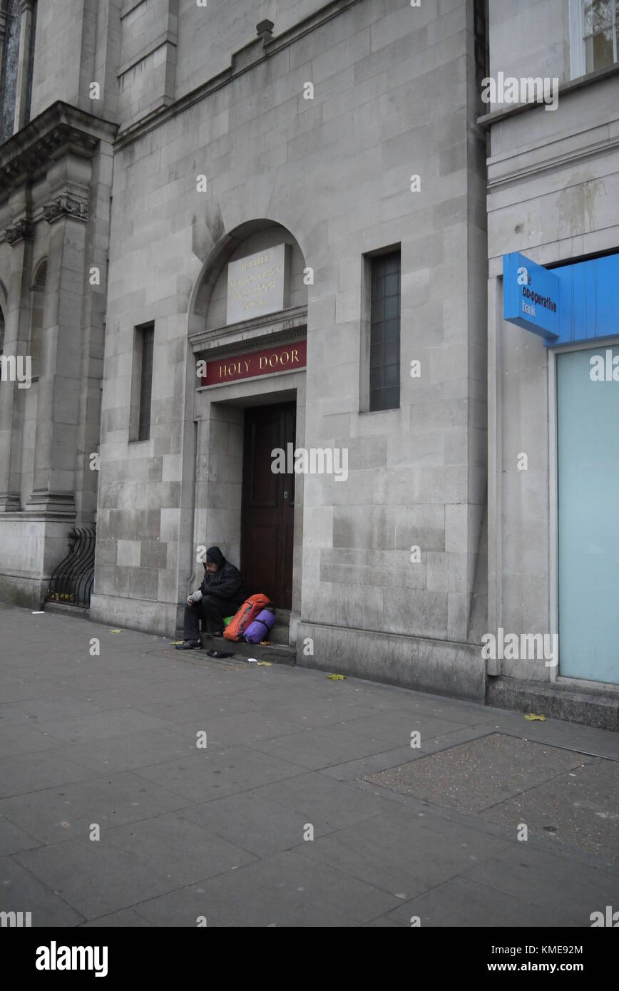 Porta Santa, Holborn, un senzatetto è seduto a mendicare, sotto il riparo della Porta Santa un monumento a un anno di misericordia Giubileo 2015-2016 Foto Stock