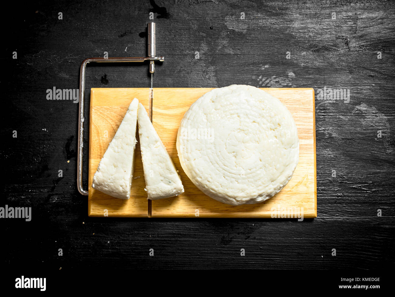 Formaggio caprino fresco su un tagliere. su un nero lo sfondo di legno. Foto Stock