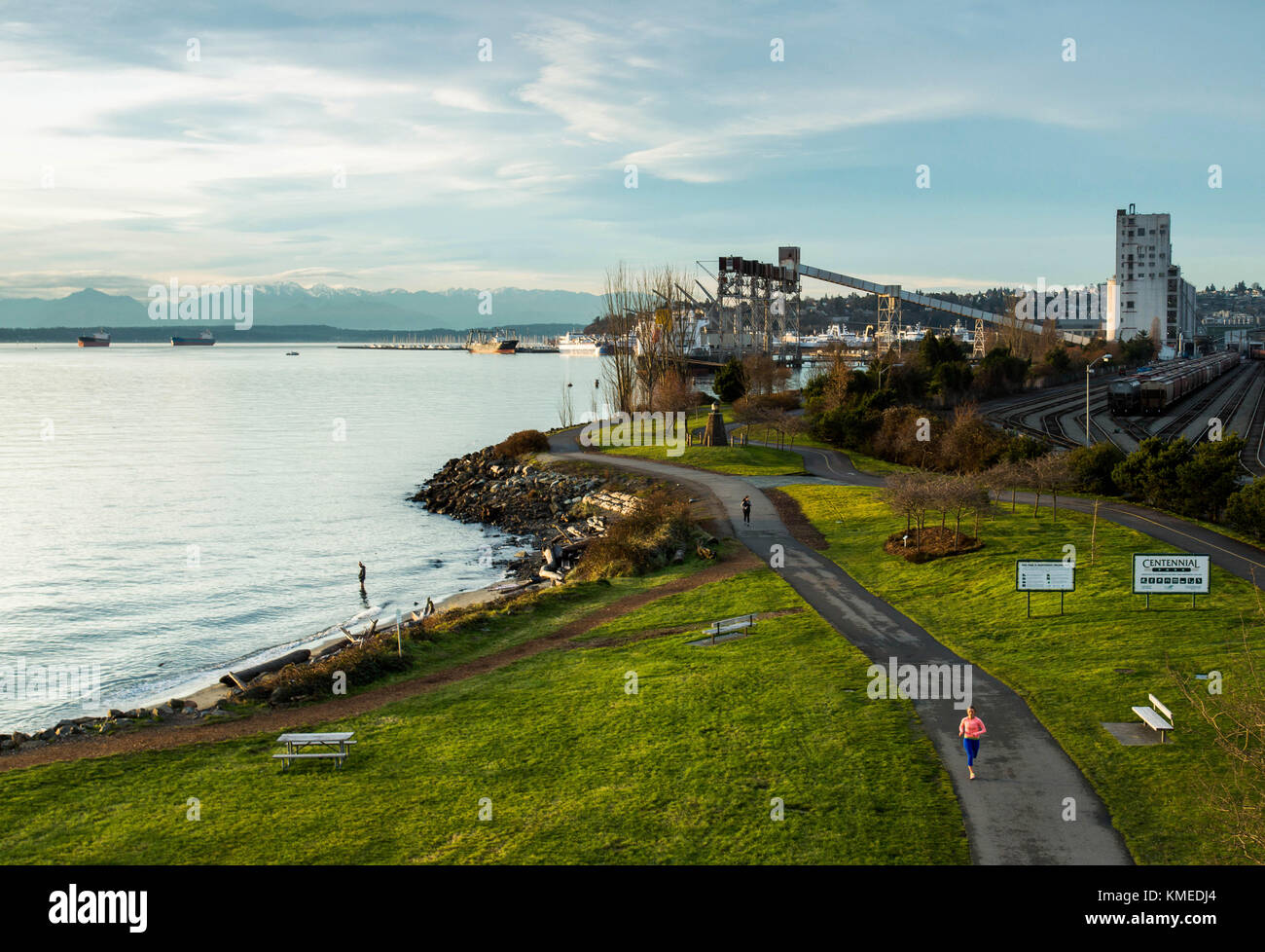 Un runner fa avanzare lungo il bordo del Puget Sound a Seattle, WA su una sera Nuvoloso. Foto Stock